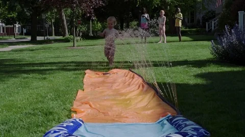 Slow motion if a toddler running through a sprinkle slider Video stock 76709612