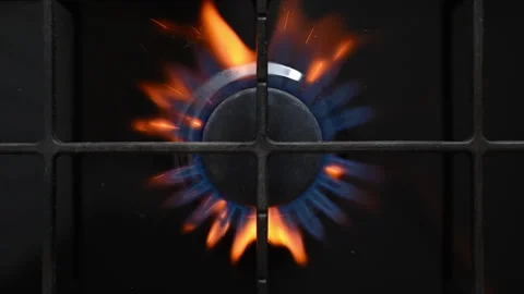 Slow-motion ignition on a black gas stove with vibrant blue-red flames. Stock Footage 318850868