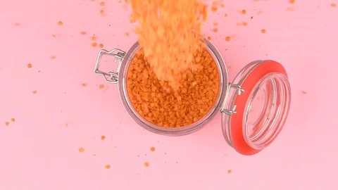 Slow motion image of lentils falling on jar glass over pastel background. 스톡 동영상 106806892