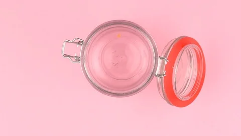 Slow motion image of lentils falling on jar glass over pastel background. Video stock 106806985