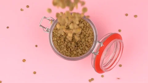 Slow motion image of lentils falling on jar glass over pastel background. Stock Footage 106807916