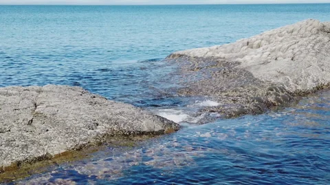 Slow-motion image of ocean waves washing over volcanic rocks Stockbeeldmateriaal 155882709
