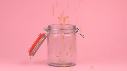 Slow motion image of popcorn falling on jar glass over pastel background. Stock Footage 106807453
