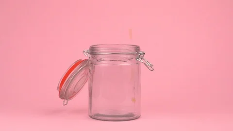 Slow motion image of popcorn falling on jar glass over pastel background. Video stock 106807571