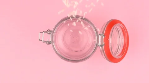 Slow motion image of rice falling on jar glass over pastel background. Stock Footage 106806968