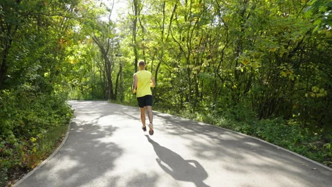 Slow motion jogger running on forked road Stock Footage 163220604