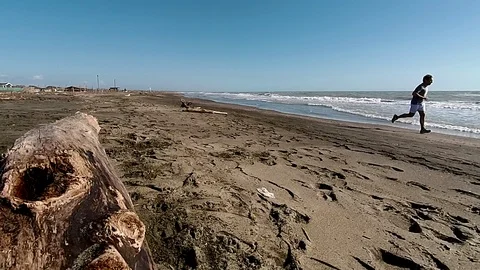 Slow Motion Jogger on a sand beach run near the sea at sunset Vidéo 87560193