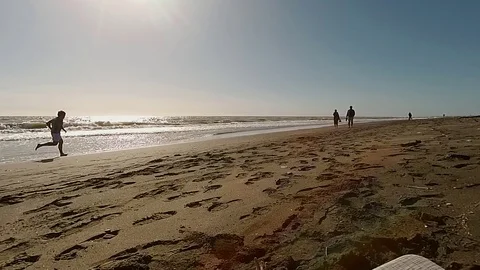 Slow Motion Jogger on a sand beach run near the sea at sunset Stock Footage 87560306