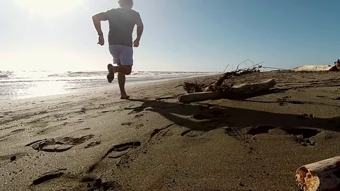 Slow Motion Jogger on a sand beach run near the sea at sunset Stock Footage 87560308