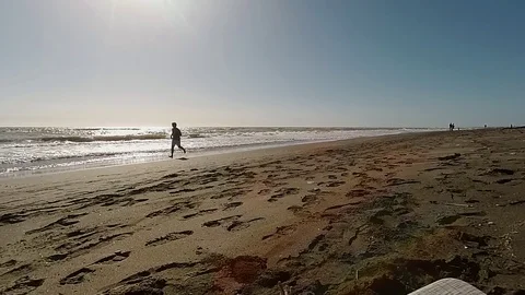 Slow Motion Jogger on a sand beach run near the sea at sunset Stock Footage 87560328