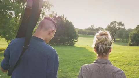 Slow motion of joyful hipster couple walking together in park at sunset. Stockbeeldmateriaal 77238143
