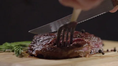 Slow motion. Juicy, fresh, appetizing beef steak cut with a knife, holding the Stock Footage 75242766