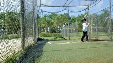 Slow motion of kid batting ball inside batting cages at baseball park Stock Footage 85653691