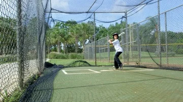Slow motion of kid batting inside batting cages at baseball park Stock Footage 85653629