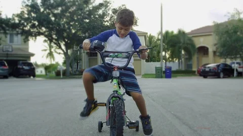 Slow motion of kid beginning to pedal and then riding bike towards camera Stockbeeldmateriaal 92211824