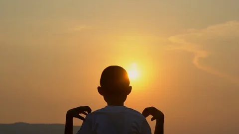 Slow motion kid boy playing exercising on morning sunrise sky background Video stock 129640053