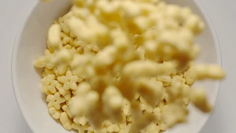 SLOW MOTION: Kid corn flakes falling into a white bowl Stock Footage 108573455