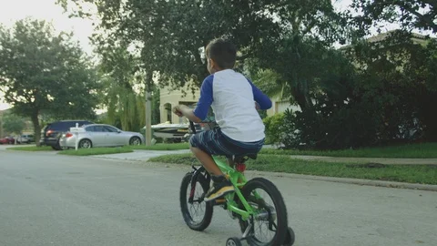 Slow motion of a kid having fun while riding a bike in a neighborhood street Stock Footage 93529225