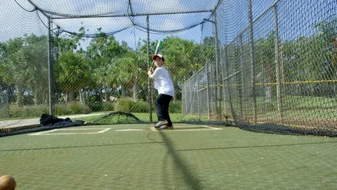 Slow motion of kid hitting ball inside batting cages at park Stock Footage 85645634