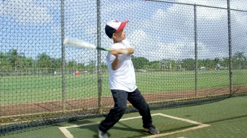 Slow motion of kid hitting ball at batting cages in baseball park Stock Footage 87810936