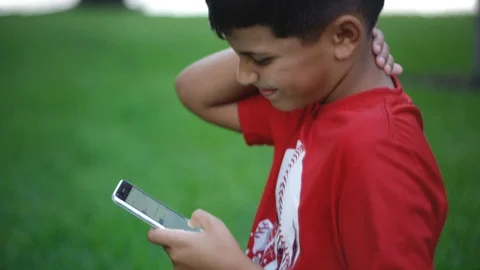 Slow motion of kid looking down at cellphone while grabbing his neck with pain Stock Footage 111049210