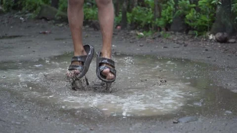 Slow Motion Kid Playing and Jumping in the Puddle of Mud on Rainy Day in the Stock Footage 132640569