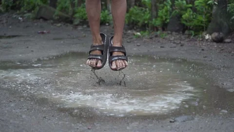Slow Motion Kid Playing and Jumping in the Puddle of Mud Rain Stock Footage 132640844