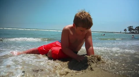 Slow motion of kid playing with sand while lying in the ocean Stockbeeldmateriaal 63889636