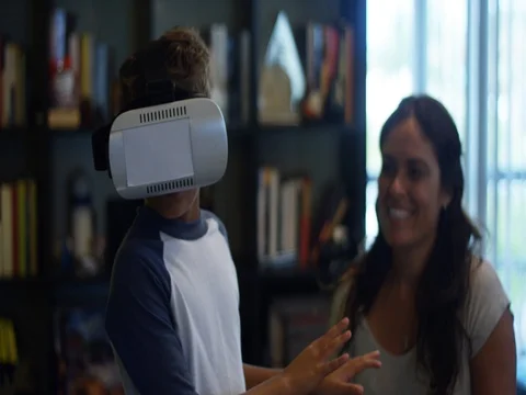 Slow Motion of Kid playing with Virtual Reality headset while mom watches Stock Footage 78687285