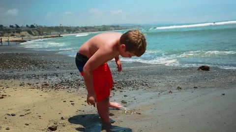 Slow motion of kid standing in front of the ocean playing with sand Stock Footage 63882151