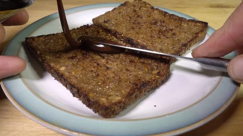 Slow motion: Knife spreading yeast extract on toasted wholegrain rye bread. Stock Footage 97731969