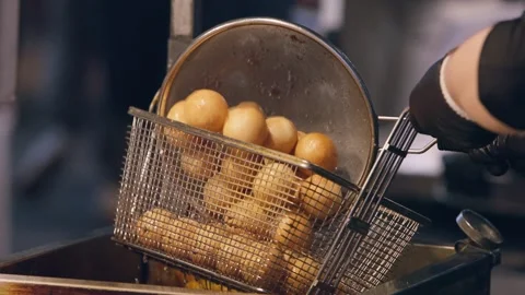 Slow motion of Korean vendor deep-frying golden potato balls on skewers  Stock Footage 313674815