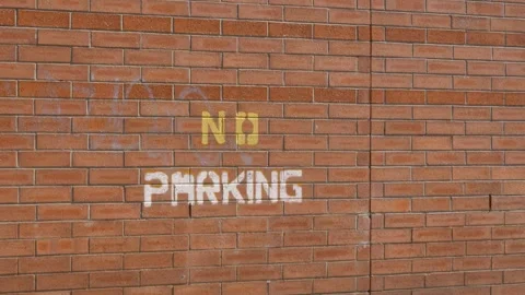 Slow motion landscape of a No Parking warning traffic sign stencil painted in Stock Footage 346882316