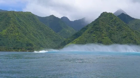 SLOW MOTION: Large raging ocean waves rush towards a mountainous exotic island. Stock Footage 94388455