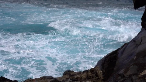 Slow motion of a large wave fringing on volcanic rocks. Vidéo 125391579