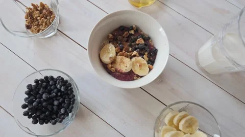Slow motion lateral shot across oatmeal breakfast with berries, banana and .. Video stock 329841989