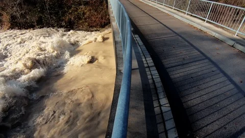 Slow motion left pan water flowing under small road bridge Stock Footage 121679748