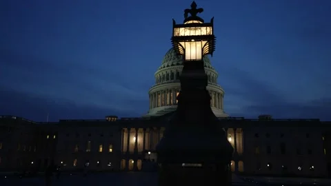 Slow motion to left showing the US Capitol with lights and flags waving in Stock Footage 238353087