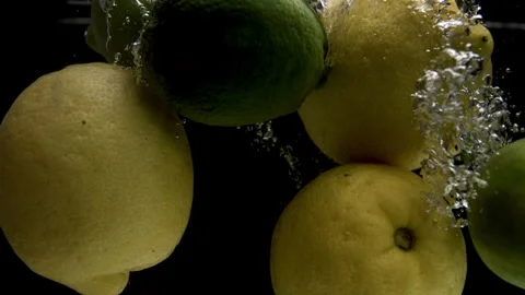 Slow Motion of Lemons and Limes Falling Into a Pool of Water with a Black Stock Footage 270408600