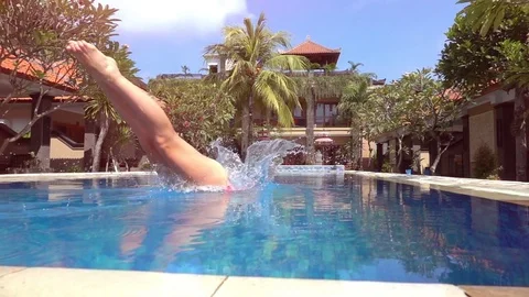 SLOW MOTION LENS FLARE: Girl in pink bikini diving head first into pool water Stock Footage 78105341