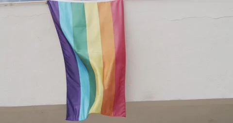 Slow motion of an LGTB flag fluttering in the wind from a window Stock Footage 133900620