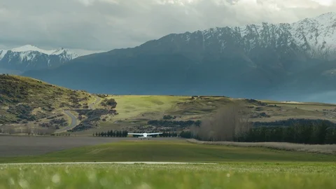 Slow motion light aircraft taking off from grass runway beside alpine mountains Stock Footage 90270083
