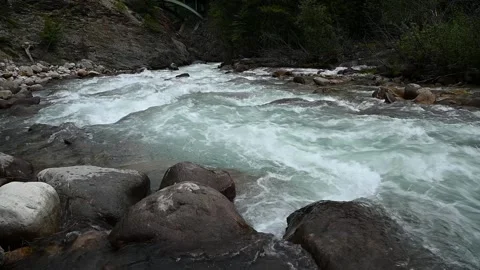 Slow motion of a light green colored river cascading over rounded boulders Stock Footage 144022625