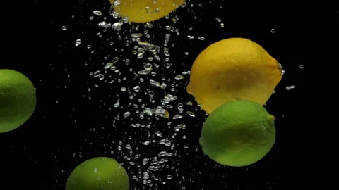 Slow motion lime and lemon falling into transparent water on black background Stock Footage 248054727