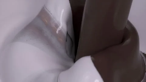 Slow motion: Liquid chocolate pouring into cream. UHD25p Stock Footage 249602769