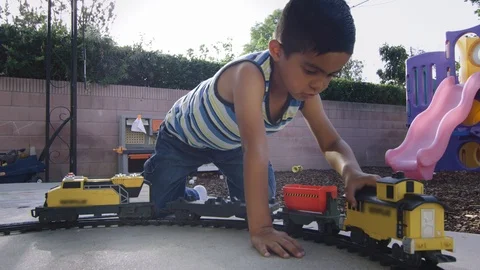 Slow motion of a little boy playing with a train set in a backyard Stock Footage 92089684