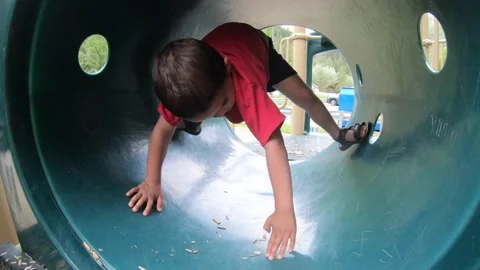 Slow motion of little boy playing in a tube at a playground on hot day Stock Footage 137655707