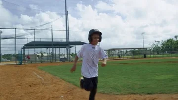 Slow motion of little boy running to first base at empty baseball park Stock Footage