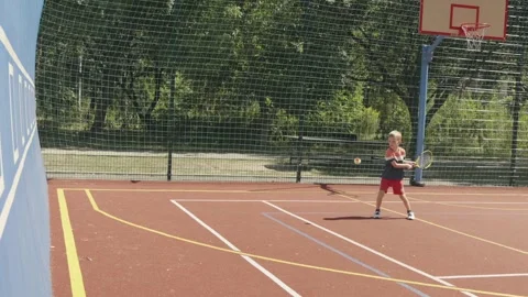 Slow motion. Little Boy Training His Tennis Skills Against a Practice Wall 動画素材 342174838