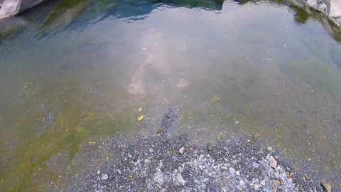 Slow motion looking down around still water pond pool standing on pile of gravel Stock Footage 266502277